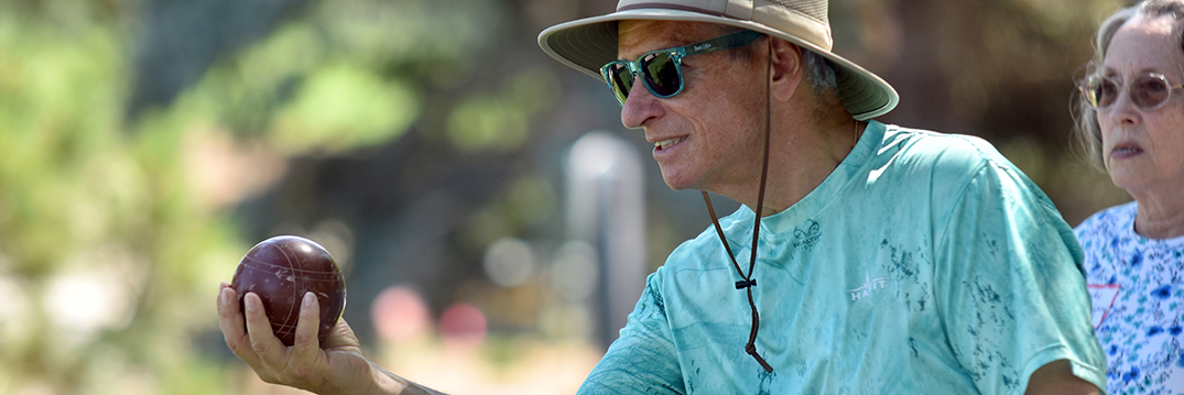 A man holding a bocce ball prepares to roll it