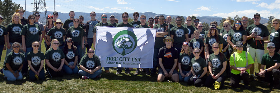 A large group of volunteers pose for a photo during an Arbor Day celebration.