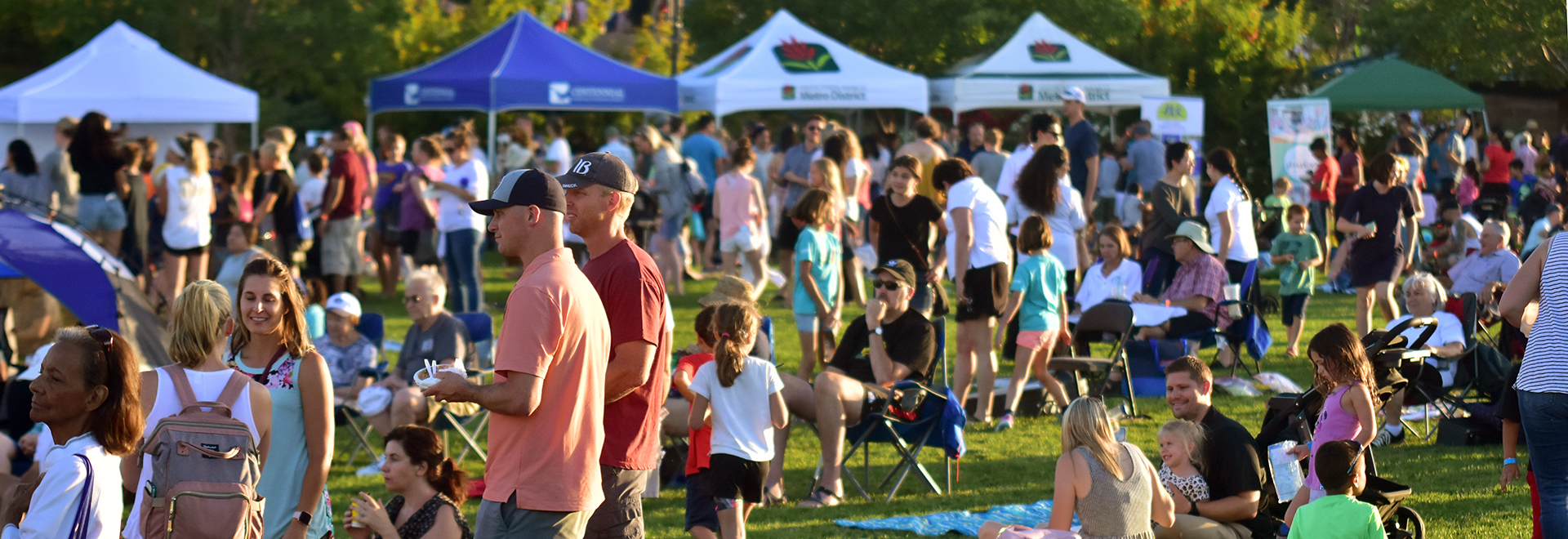 A large crowd mills around Civic Green Park amongst vendor tents and picnic blankets during the Ice Cream Social.