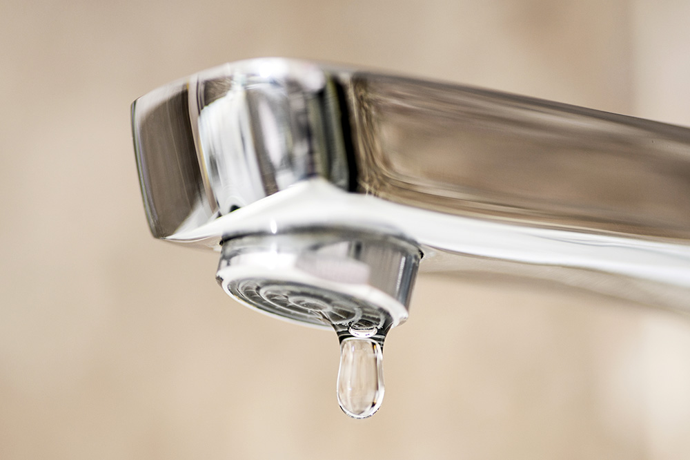 A water faucet with a drip of water