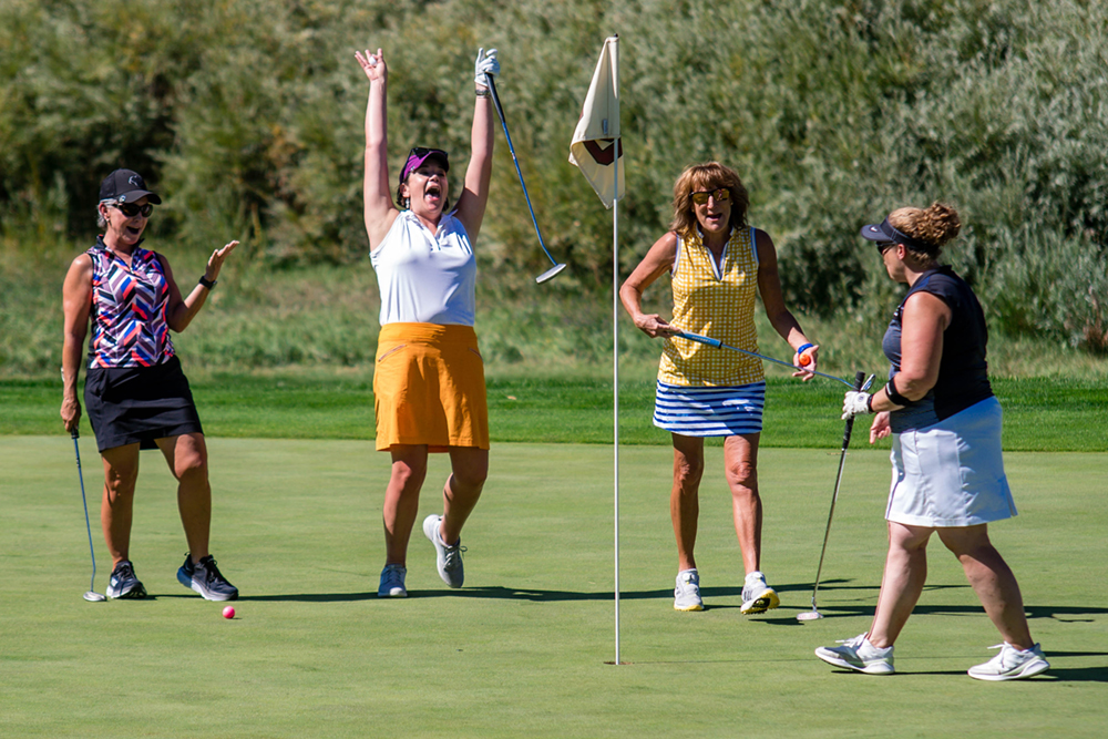 Four golfers cheering after a putt during the Highlands Ranch Metro District annual benefit golf tournament