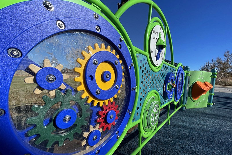 Brightly colored interactive playground panels including gears to rotate and musical instruments to play.