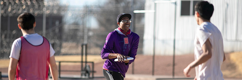 Young adults playing ultimate frisbee and smiling.