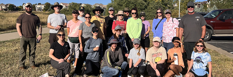 A group of more than 20 adults and teens pose for a group photo during an open space cleanup.