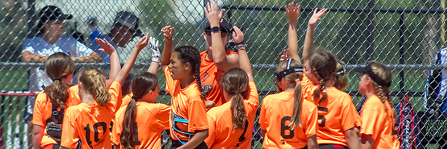 Girls softball players huddle up to do a cheer after winning a game.