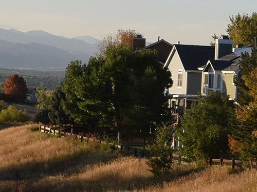 Highlands Ranch homes back to a green belt open space with blue mountains in the background.